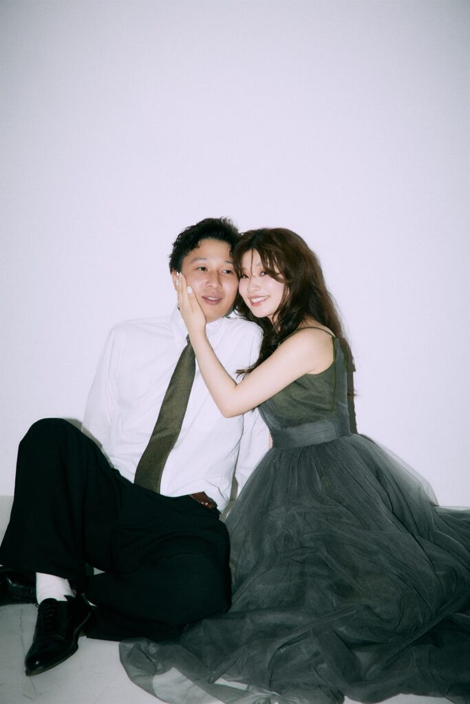 床に座って寄り添う新郎新婦のスタジオフォト