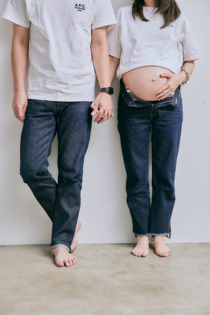 デニム姿で手をつなぐ夫婦のマタニティフォト