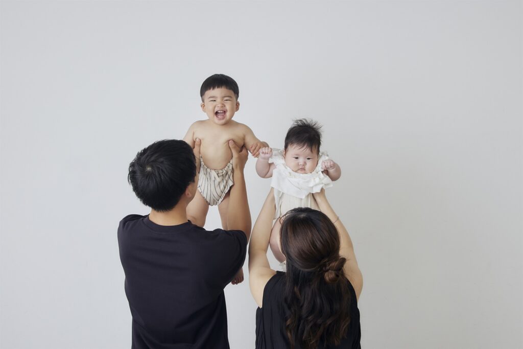 赤ちゃんを高く持ち上げる家族写真